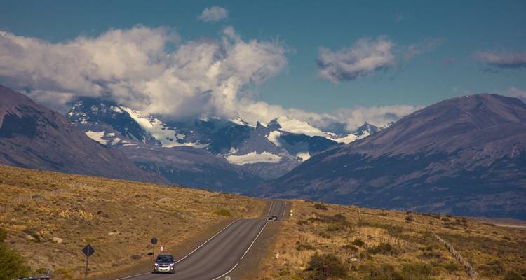 Route ouverte menant vers des pics andins spectaculaires couverts de neige sous des nuages clairsemés.