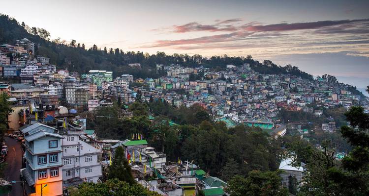 Panoramablick auf die dicht gedrängten bunten Häuser von Gangtok am Berghang bei Sonnenaufgang.