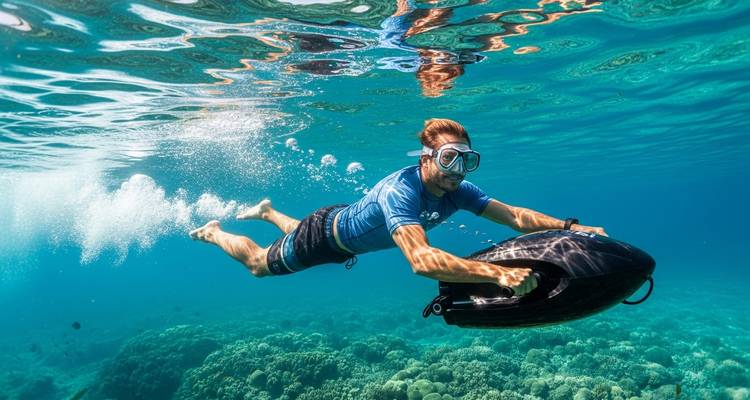 Image sous-marine d'un homme chevauchant un scooter électrique marin au-dessus d'un fond marin corallien dans une eau cristalline.