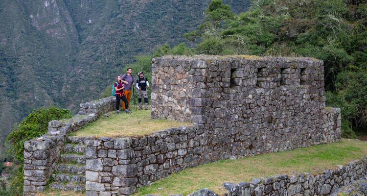Groupe de randonneurs fait une pause près d'épais murs de pierre incas perchés en hauteur au-dessus d'une vallée verdoyante