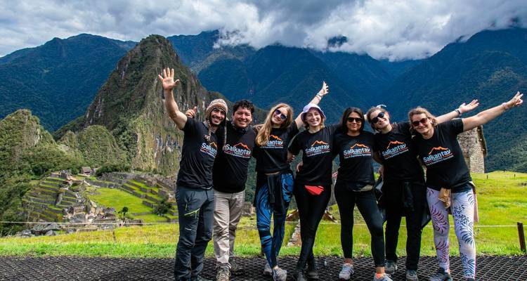 Cheerful group of hikers celebrating at a Machu Picchu viewpoint with lush peaks behind them