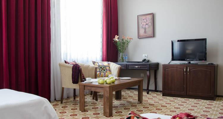 Hotel seating area with armchairs, fruit platter and television (duplicate).