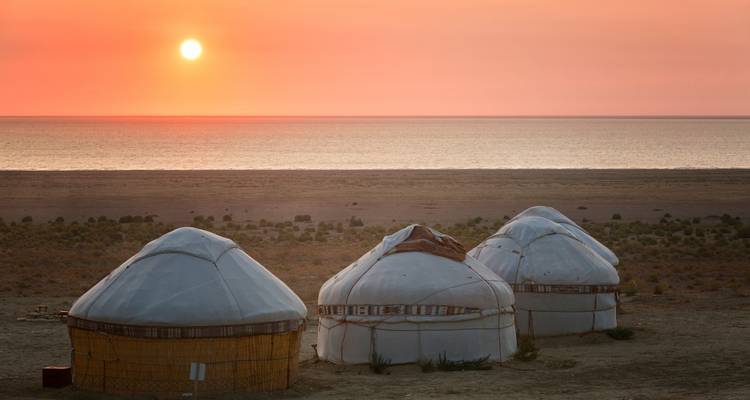 Three yurts silhouetted at sunset beside a calm lake (duplicate of 16910878).