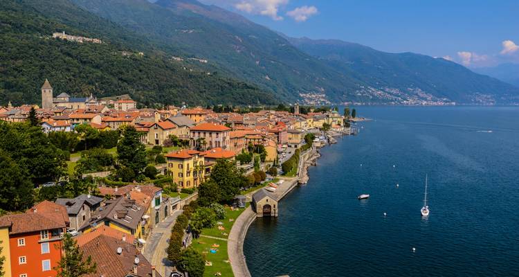 Village pittoresque au bord du lac avec des maisons colorées bordant le lac de Côme bleu profond contre les montagnes vertes