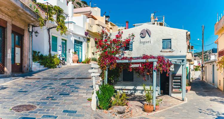 Malerische Dorfstraße am Hang mit weiß getünchten Häusern, Steinpflaster und leuchtender Bougainvillea.