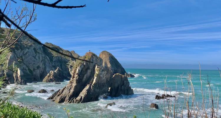 Grillige rotsformaties rijzen op uit turquoise branding onder een heldere blauwe hemel