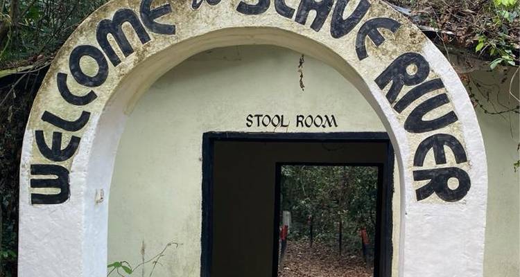 Arched entrance reading 'Welcome to Slave River' leading into a forested memorial site.