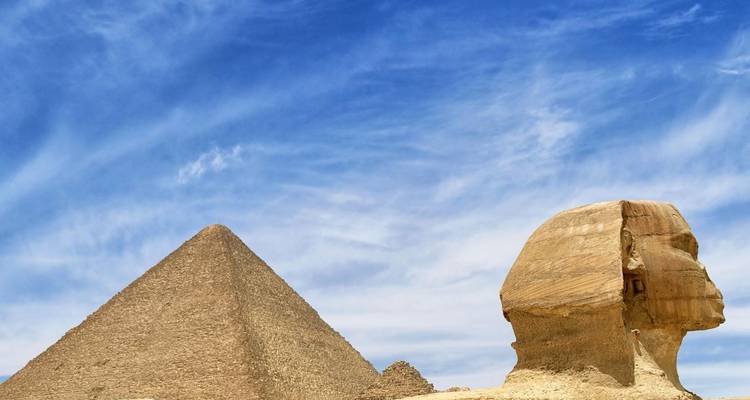 Classic profile of pyramid and sphinx under vivid blue sky on the Giza Plateau.