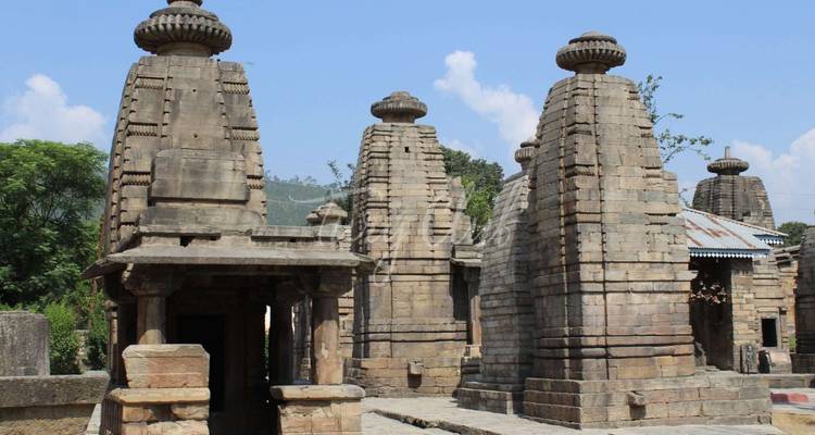 Oud stenen tempelcomplex met meerdere shikhar torens onder blauwe lucht