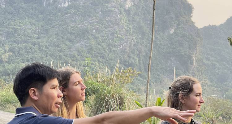El guía hace gestos mientras explica el paisaje de karst que rodea a dos viajeros.