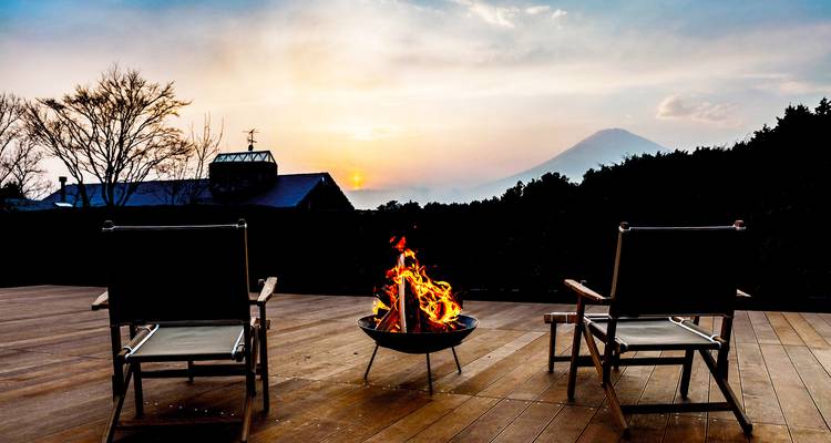 Lumière de l'aube et feu crépitant sur une terrasse en bois avec vue dégagée sur le mont Fuji