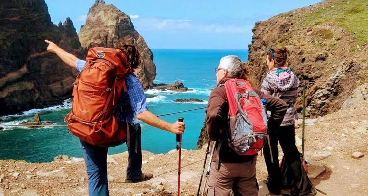 Führer zeigt auf Felstürme, während Wanderer schroffe Küstenklippen und türkisfarbenes Wasser bewundern