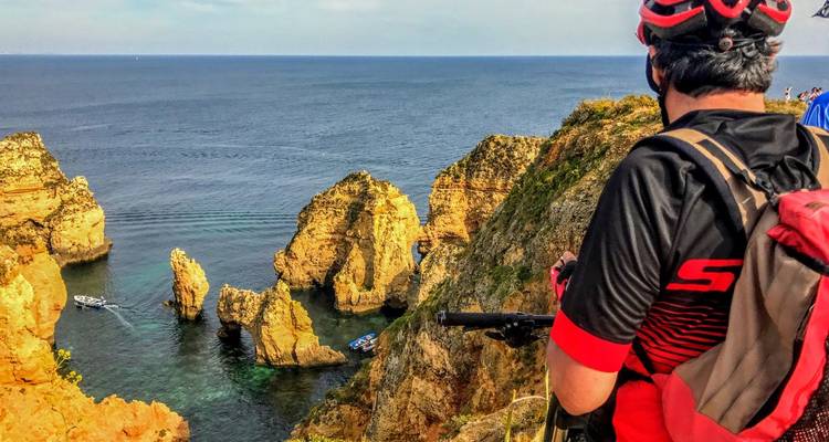 Radfahrer hält an, um die ikonischen Felsnadeln von Ponta da Piedade von einem hohen Klippenaussichtspunkt zu bewundern