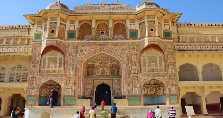 Bezoekers naderen de sierlijke, met fresco's versierde Ganesh Pol poort van Amber Fort onder het felle zonlicht.