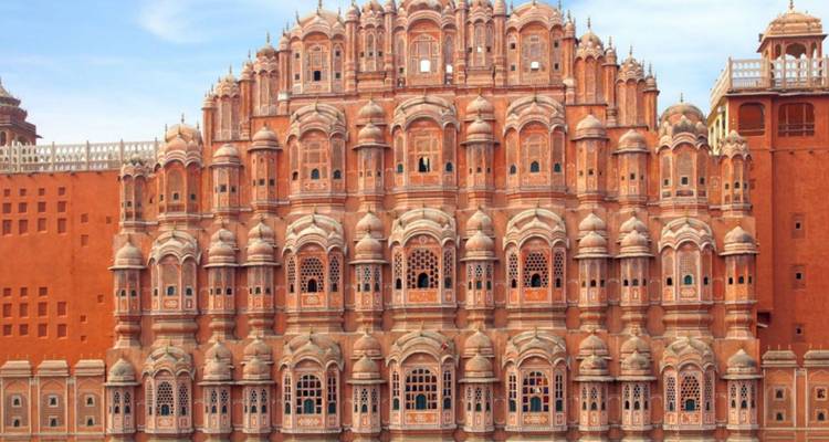 Voorgevel van de roze zandsteen Hawa Mahal met zijn ingewikkelde tralievensters onder een heldere hemel.