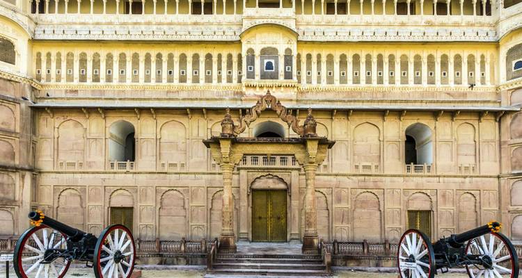 Dos cañones históricos flanquean la entrada con arco ornamentado de la fachada de piedra arenisca del Fuerte Junagarh.