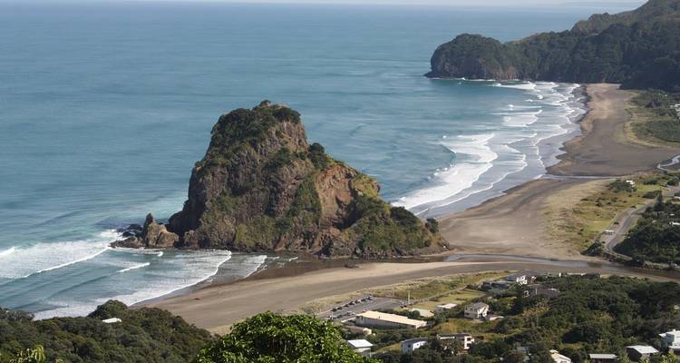 Erhöhte Ansicht einer zerklüfteten Küstenlinie mit Lion Rock und schwarzem Sandstrand darunter