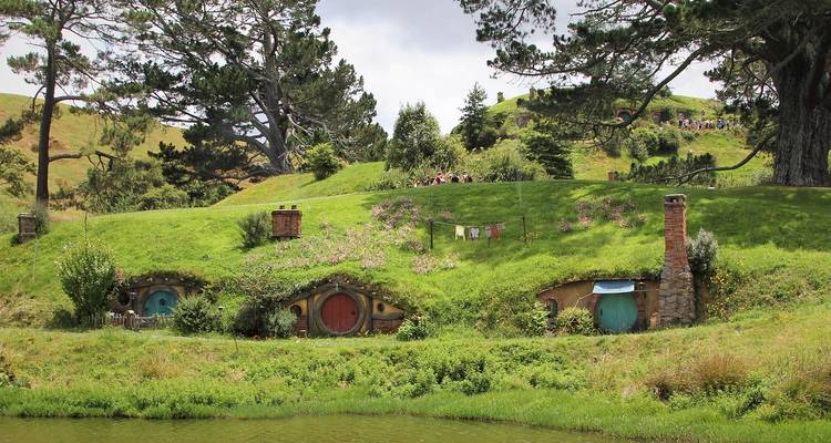 Malerische Hobbiton-Hobbithöhlen, die in einen grasbewachsenen Hügel nahe einem Teich hineingebaut sind