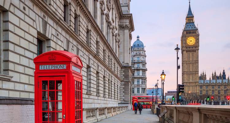 Cabina telefónica roja clásica en una calle de Londres con Big Ben y Westminster a la vista.