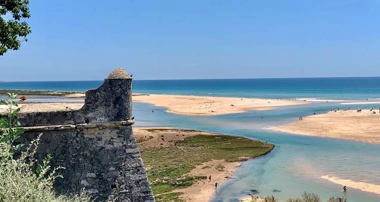Steinerner Festungsturm mit Blick auf eine Sandbank, wo eine Lagune auf den tiefblauen Atlantik trifft.