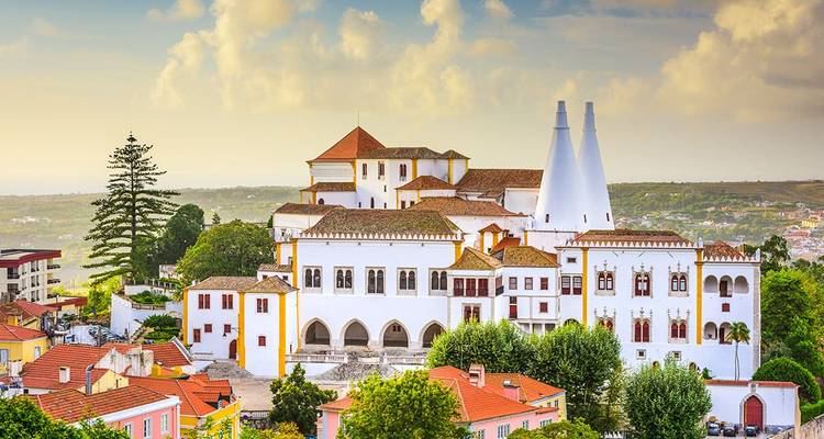 Weißer Nationalpalast mit zwillingsförmigen konischen Schornsteinen, die sich über die Dächer der Stadt Sintra erheben.