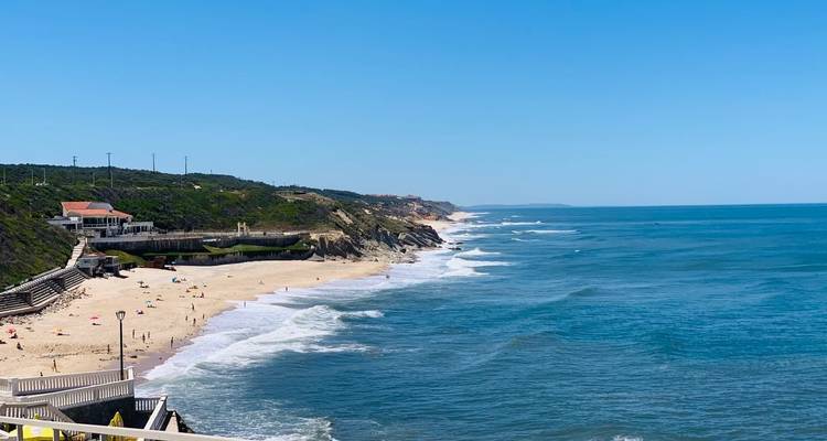 Lange Küstenstrecke am Atlantik mit goldenem Sandstrand und sanften Wellen an einem sonnigen Tag.