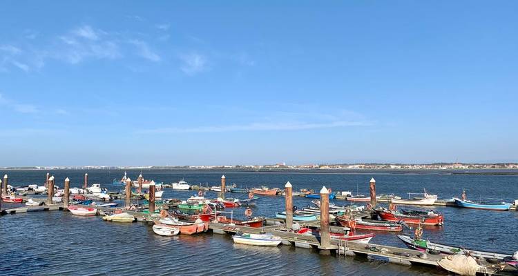 Kleine Fischerboote, die an einem windigen Hafen angelegt sind, mit einer entfernten Stadt auf der anderen Seite des Wassers.