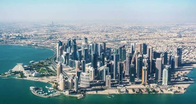 Luftaufnahme von Dohas moderner West Bay Skyline, die in den Persischen Golf hineinragt mit geschwungener Küstenlinie.