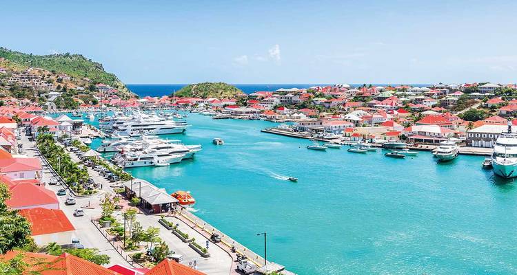 Türkisfarbener Hafen voller Yachten und rotbedachter Gebäude, die die Uferpromenade an einem sonnigen karibischen Tag säumen