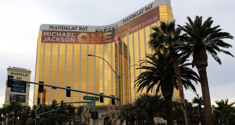 Torre de cristal dorado del hotel Mandalay Bay enmarcada por palmeras.