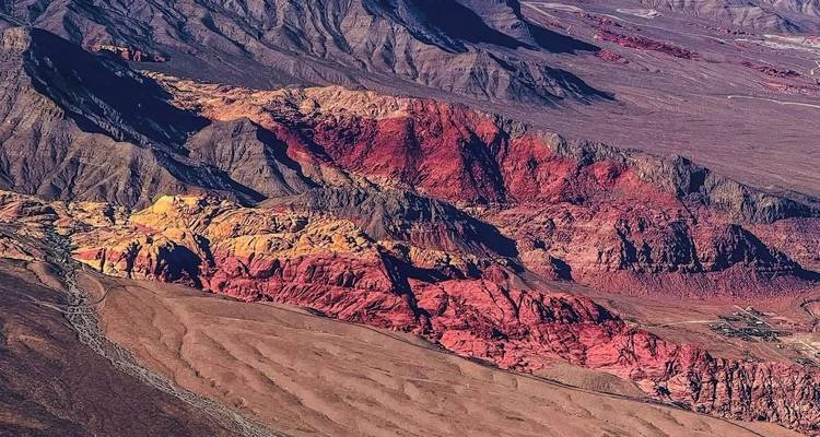 Paisaje aéreo colorido de capas de crestas desérticas rojas, amarillas y púrpuras.