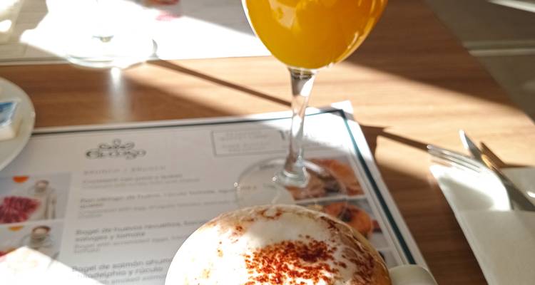 Gros plan d'un cappuccino garni de cacao et d'un verre de jus d'orange sur une table de café