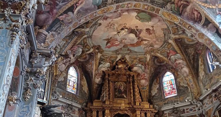 Intérieur d'église baroque richement décorée avec plafond peint, vitraux et autel doré