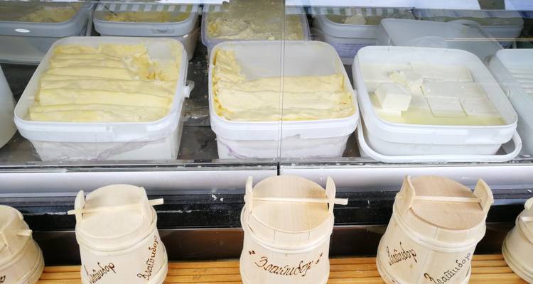 Vitrine de pâte à fromage fraîche feuilletée et blocs de fromage tendre dans des bacs à un étal de produits laitiers.
