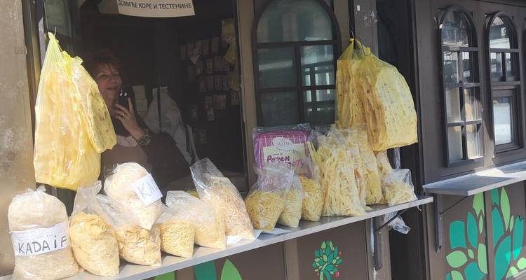 Vendeur derrière un étal vendant des sacs de pâtes séchées artisanales suspendus au plafond.