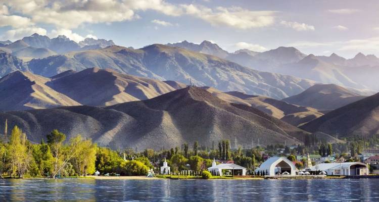 Lac scintillant bordé d'une petite ville de villégiature avec une chaîne de montagnes imposantes en arrière-plan