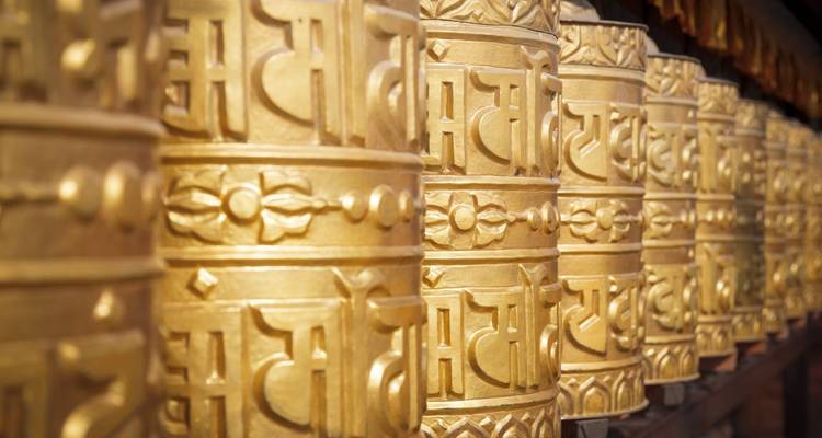 Rijen van sierlijke gouden boeddhistische gebedswielen glinsteren in het zachte licht.