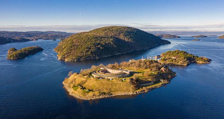 Vue de drone d'une forteresse insulaire et du fjord d'Oslo environnant parsemé de collines boisées et d'eau bleue.
