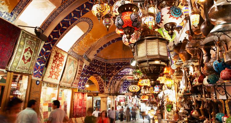 Levendige lantaarn- en koperwinkels in Istanbuls Grote Bazaar met wazige menigtes die erdoorheen lopen.