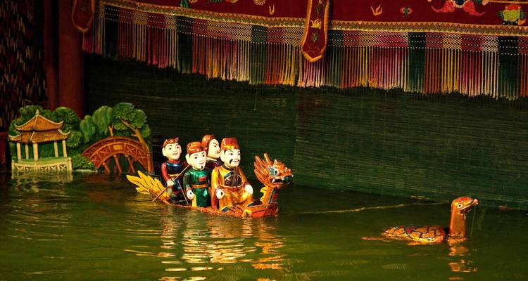 Houten waterpoppenfiguren die in een drakenboot over een groen getint podiumbassin varen