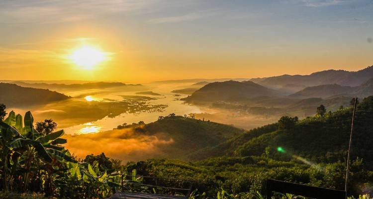 Spectaculaire zonsopgang over mistige Mekong vallei met gloeiende rivierbochten en groene bergen.