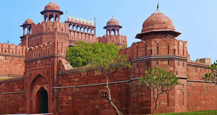 Las históricas murallas y cúpulas de arenisca roja del Fuerte Rojo de Delhi se alzan contra un cielo despejado.
