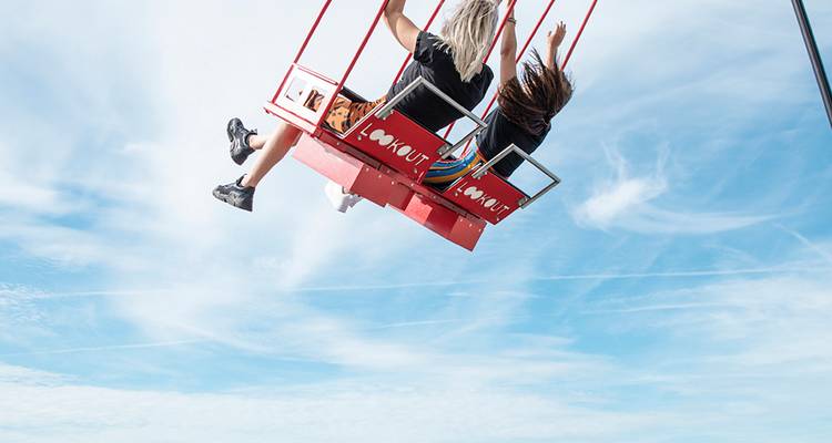 Deux personnes s'élèvent sur la balançoire de l'A'DAM Lookout haut au-dessus d'Amsterdam contre un ciel bleu