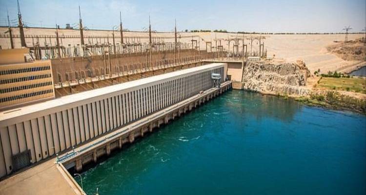 Wide view of the Aswan High Dam complex with turquoise water below concrete walls.