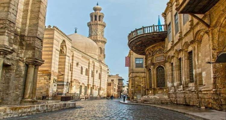 Historic Islamic Cairo street lined with ornate stone architecture and a towering minaret.