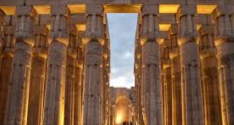 Illuminated stone columns of Luxor Temple glowing against the twilight sky.