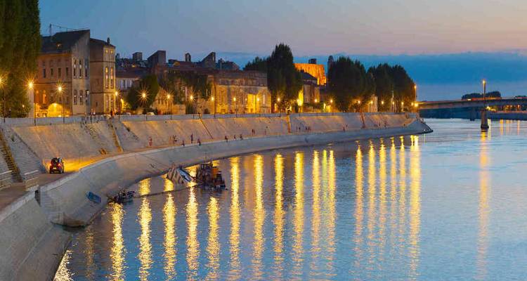 Promenade au bord de la rivière doucement éclairée au crépuscule avec des reflets dansant sur l'eau calme dans le sud de la France
