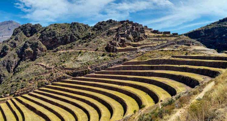 Famous agricultural terraces of Pisac sweeping along mountain ridge under blue sky.