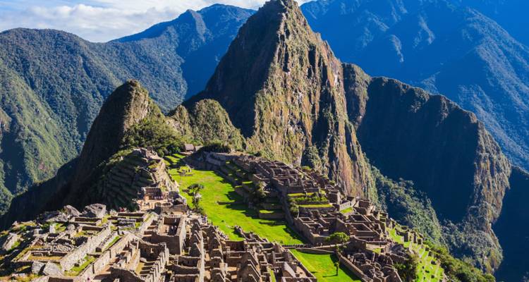 Classic postcard aerial of Machu Picchu ruins with dramatic Andean ridge backdrop.