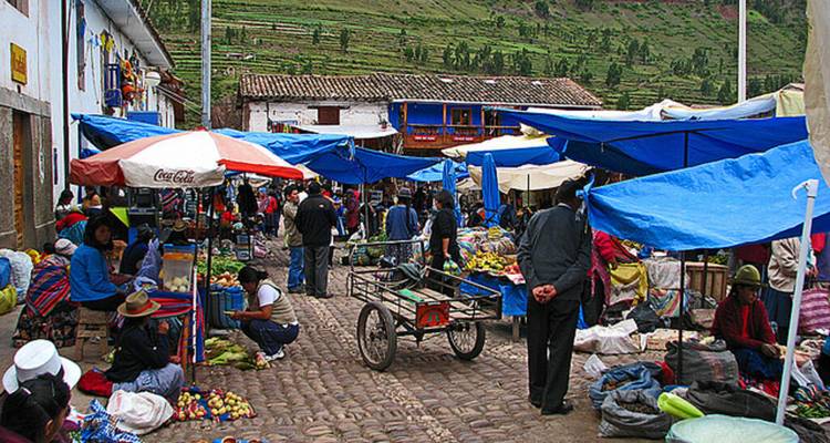 Crowded local market with blue tarps, vendors and colorful produce in the Sacred Valley.